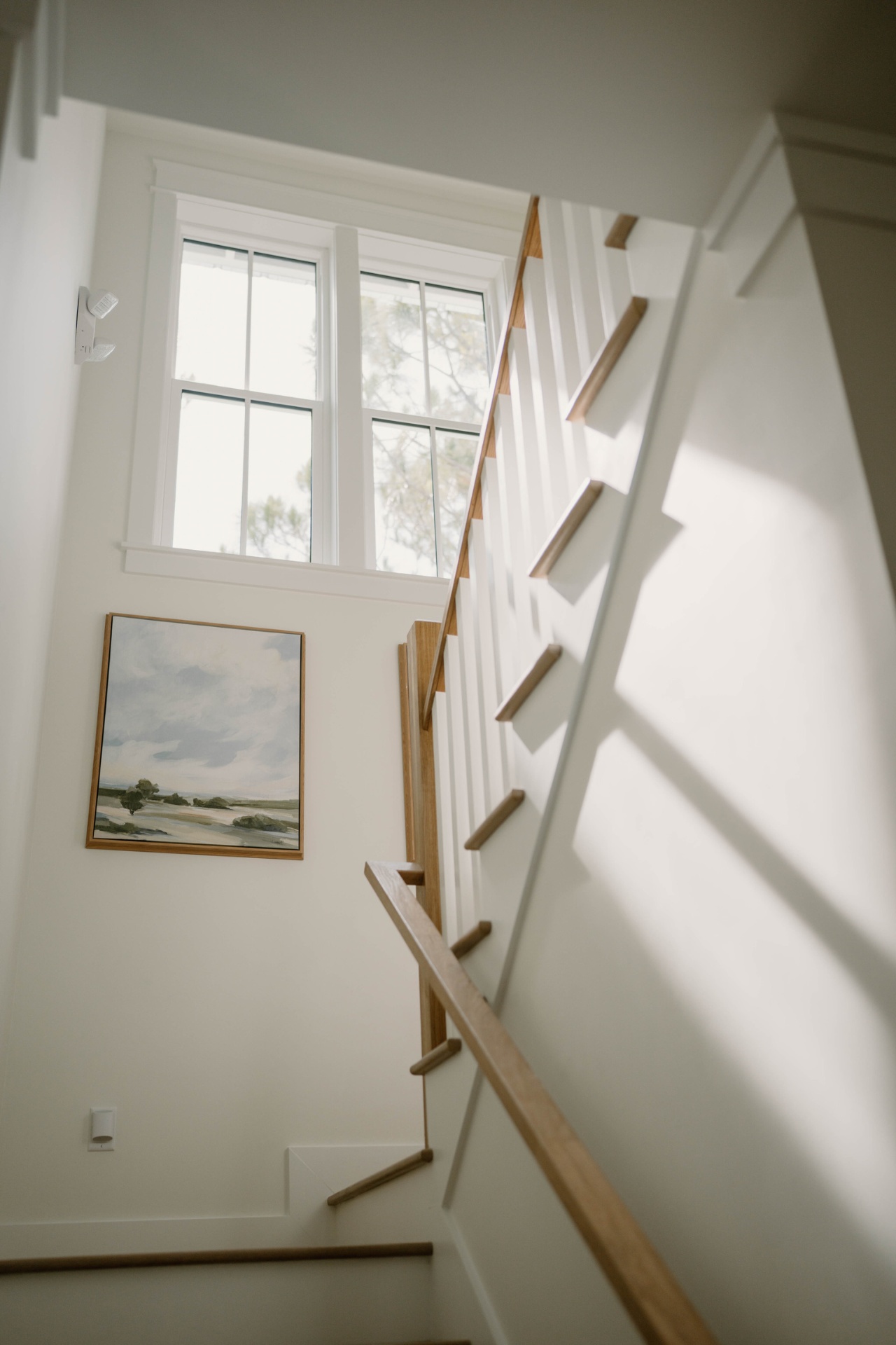 Sunlit staircase with coastal landscape art